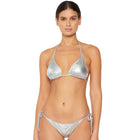 A woman modeling a metallic silver string bikini against a plain light gray studio background.