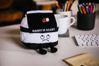 Plush toy with 'Dairy is Scary' text on a desk with coffee mug and pens.