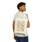A man wearing a white t-shirt and blue jeans is shown from the back, carrying a cream canvas tote bag over his shoulder. The tote bag features a colorful, playful 'Los Angeles' graphic filled with illustrations of palm trees, hearts, and beach-themed icons.