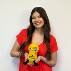 Woman in a red dress holding a yellow toy with a face design against a white background