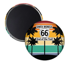 Two round magnets on a white background, showing the front and back. The front magnet features a retro sunset design with black palm tree silhouettes, a Route 66 sign reading 'Santa Monica' and 'End of the Trail', and horizontal bands of red, orange, yellow, beige, teal, and black.