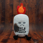 Plush toy with flame on top and 'Not a Happy Camper' text on a wooden background