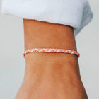 Braided bracelet on a wrist with a neutral background