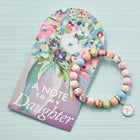 Floral-themed card with 'A Note to My Daughter' text and a colorful beaded bracelet on a light blue background.