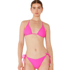 Woman wearing a bright pink bikini set against a white background