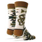 A pair of crew socks with a white base, featuring a green and brown coiled snake graphic, geometric patterns, and brown ribbed cuffs and heels, displayed on invisible forms against a white background.