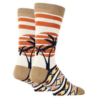 A pair of crew socks with a tropical sunset design, featuring orange and white horizontal stripes, black palm tree silhouettes, and a multicolor geometric pattern on the foot.