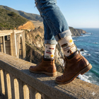 Person wearing jeans and socks with a scenic ocean view in the background