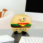 Plush burger toy with a smiley face on a desk