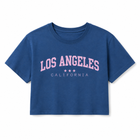 A blue short-sleeve crop top t-shirt featuring 'LOS ANGELES CALIFORNIA' printed in pink on the front, displayed against a solid white background.