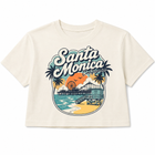 An off-white cropped short-sleeve t-shirt featuring a colorful retro-style graphic of the Santa Monica Pier in California, complete with palm trees, a Ferris wheel, and ocean waves.