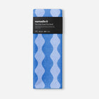 Blue towel with wavy pattern and 'nomadix' branding on a white background