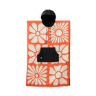 Floral patterned pouch with a black tag on an orange background