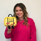 Woman holding a yellow emotional baggage plush toy against a white background
