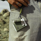 Green sewing kit with thread and needle on a person's lap outdoors