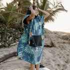 Person wearing a blue tropical patterned poncho on a beach