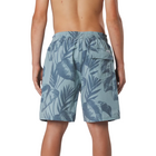 Rear view of a person wearing light blue swim trunks with a dark blue tropical leaf pattern, shown against a light gray studio background.