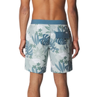 Rear view of a man wearing board shorts with a tropical leaf print in shades of blue, green, and white, featuring a solid blue waistband and a side pocket.