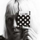 Person holding a black wallet with white polka dots in front of their face