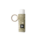 A lip balm tube wrapped in a beige knit pattern sleeve with a black logo patch, attached to a gold key ring, on a light gray background.