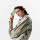 Woman holding a green phone with a white background