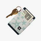 Cardholder with star pattern, key, and dollar bill on a white background