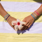 Hands holding a flower on a yellow and white striped fabric
