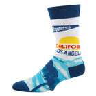 A single crew sock with a Los Angeles beach-themed graphic print. The sock features a white upper section with blue 'Los Angeles' script, a yellow and red sunset graphic, and 'CALIFORNIA LOS ANGELES' text, transitioning into a blue and light blue palm tree pattern on the foot.