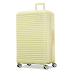 A pale yellow hard-shell spinner suitcase with a ribbed texture, telescoping handle, and four wheels, shown on a plain white background.