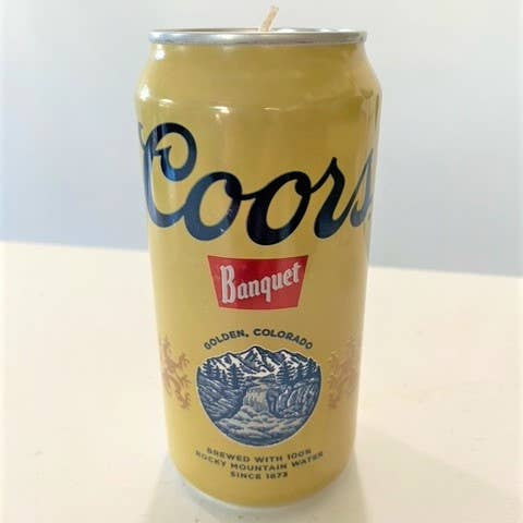 Coors Banquet beer can candle on a white surface with a light blue background