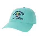 A mint green baseball cap featuring an embroidered 'Santa Monica California' design with palm trees and a sunset on the front panel, set against a plain white background.