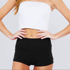 Woman wearing a white strapless top and black shorts on a plain background