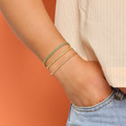Model wearing multiple colors of Pura Vida Goldie Woven Seed Bead Bracelet