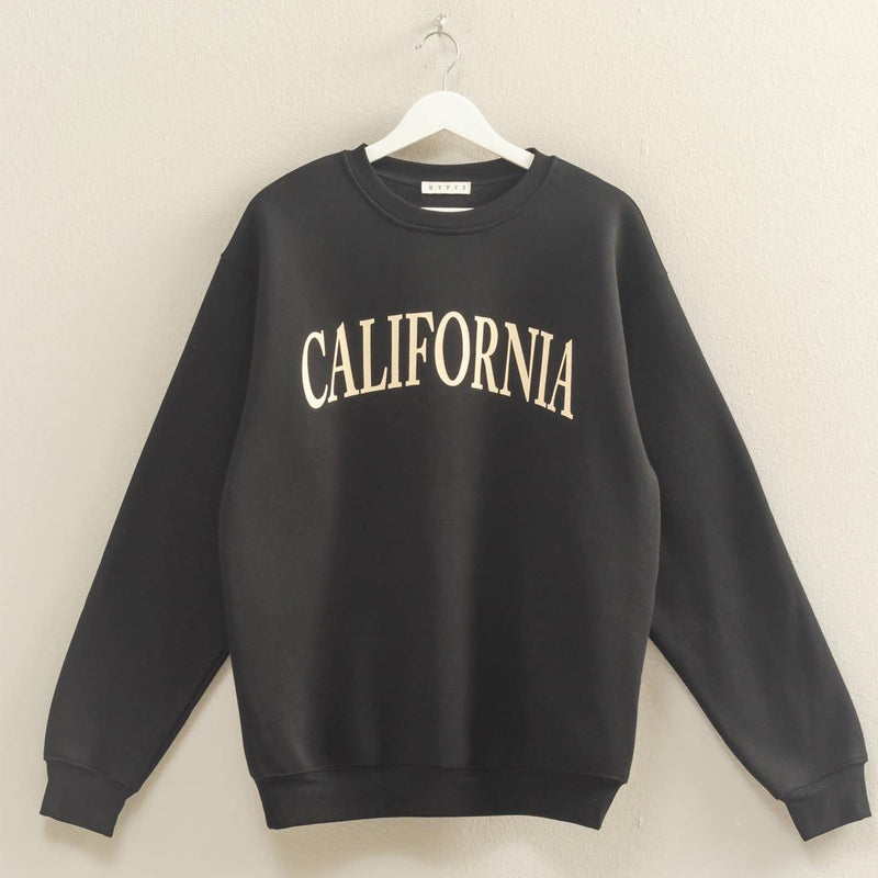 Black sweatshirt with 'CALIFORNIA' text on a hanger against a beige wall.