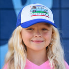 A young girl with long blonde hair wearing a blue and white trucker hat with a California-themed graphic, set against a blue background.