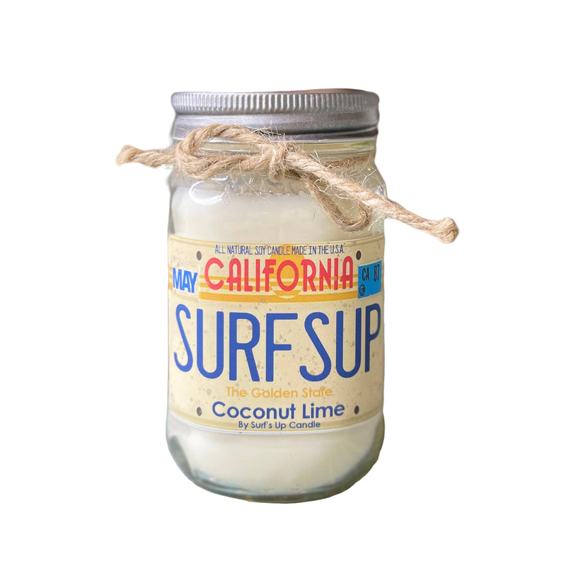 Jar of 'Surf's Up' coconut lime candle on a wooden surface with a blurred background