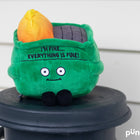 Green plush toy with a solar panel on top, sitting on a black surface.