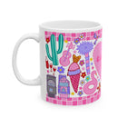White mug with colorful graphics including a cactus, ice cream, and castle on a pink checkered background.