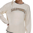 Woman wearing a cream sweatshirt with 'California' text on a plain background