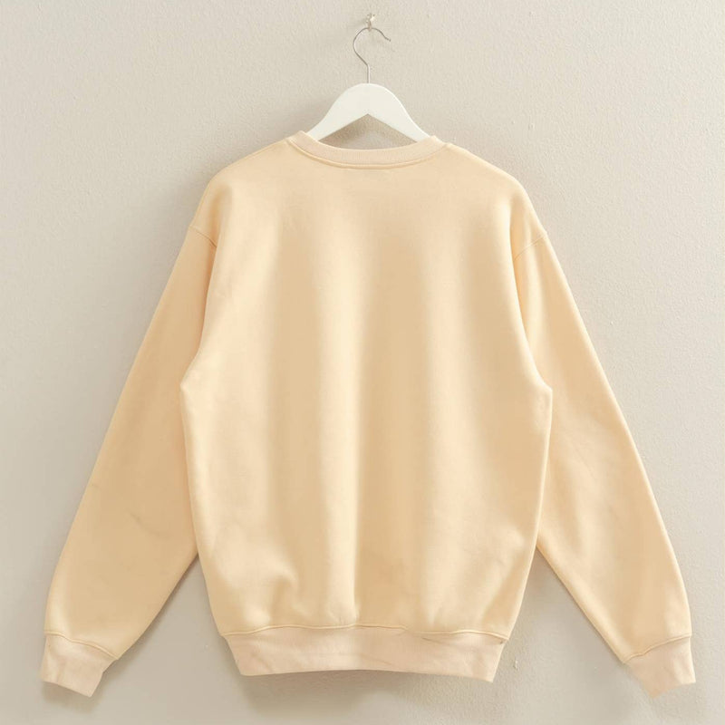 Beige sweatshirt on a hanger against a plain wall