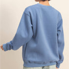 Person wearing a blue sweatshirt and denim shorts on a beige background