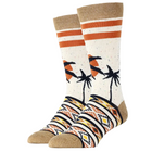 A pair of crew socks with a tropical beach theme, featuring black palm tree silhouettes and orange sun motifs on a speckled cream background, with a multicolor geometric pattern on the lower half and tan heels, toes, and cuffs.