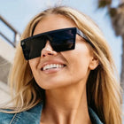 Woman wearing sunglasses with a blurred background of a building and trees