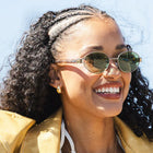 Woman wearing sunglasses and a tan coat with a blurred background