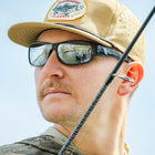 Man wearing a cap and sunglasses with a clear blue sky background