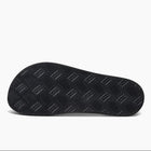 A close-up, top-down view of a black textured shoe sole with a herringbone pattern, set against a clean white background.