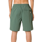 A person shown from the back wearing sage green swim trunks with an elastic waistband and a zippered pocket on the right side, against a light gray studio background.