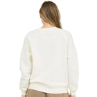 Person wearing a cream sweater and beige shorts on a white background