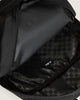Close-up of the interior of a black backpack, showing a zippered compartment, smooth black fabric lining, and a black-and-gray checkered patterned pocket with a small white logo tag.