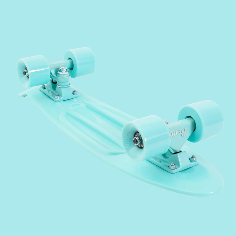 An underside view of the mint Penny skateboard, displaying the trucks, wheels, and structural details of the plastic deck.